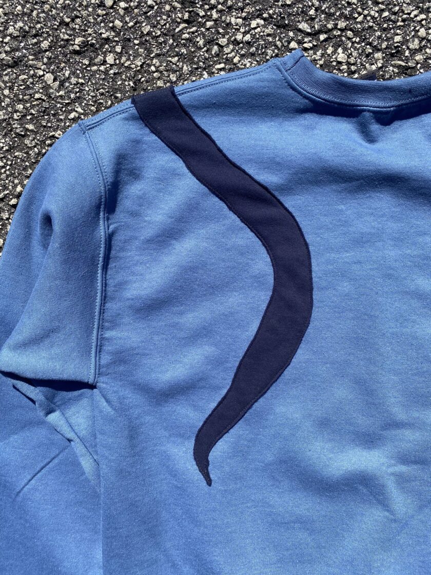 a blue t - shirt with a curved design on it.