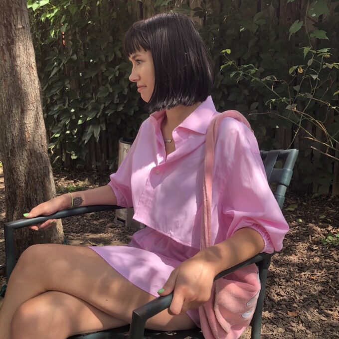 A woman in the Pretty In Pink 2 piece shirt skirt set sitting on a bench.