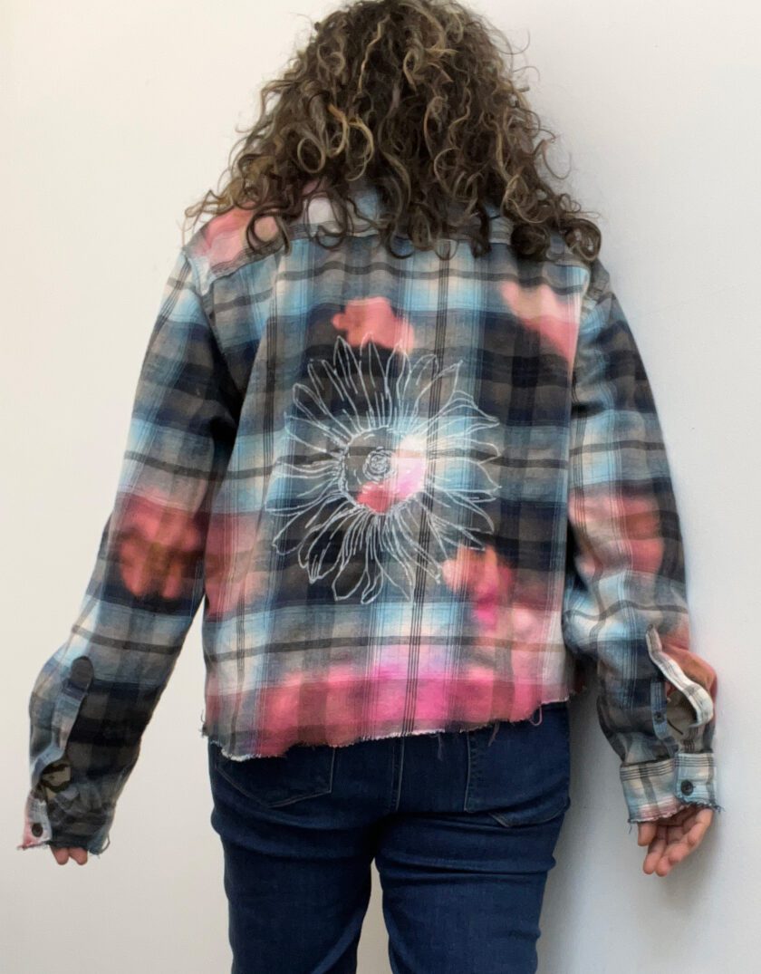a woman standing against a wall with her back to the camera wearing a Sunflower Bleached Flannel.