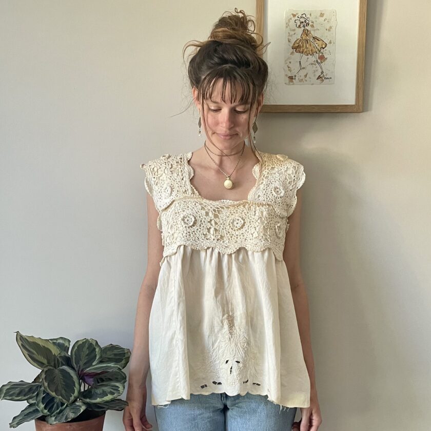 A woman standing next to a Tea Stained Cream Crochet Festival Tank Top w/ Tie Back.
