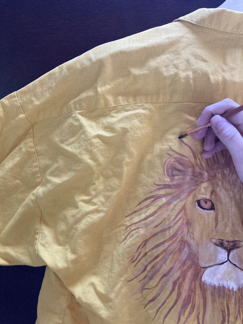 a person drawing a lion on a yellow shirt.