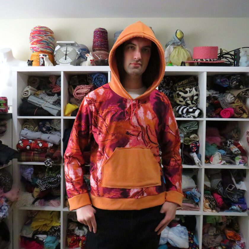 A man standing in front of a Marbled Orange Hoodie (X-Large) filled closet.