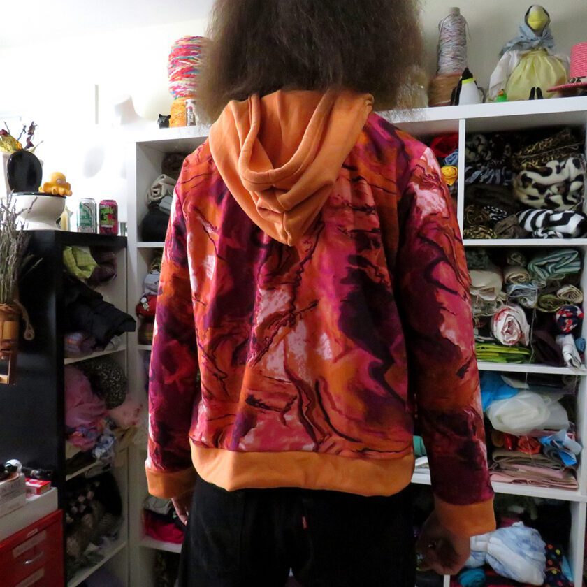 a person standing in a room with a shelf full of Marbled Orange Hoodies (X-Large).