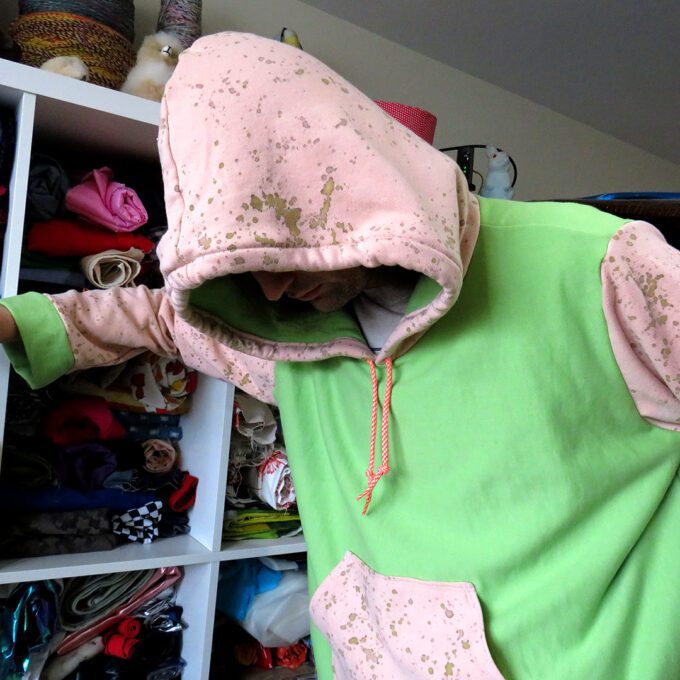 a person in a Green and Rusty Pink Hoodie (2X-Large) in a closet.