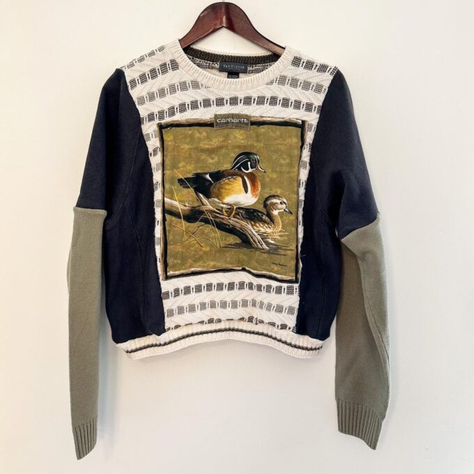 A Neutral Duck & Carhartt Grandpa Sweater Rework with a bird on it hanging on a wall.