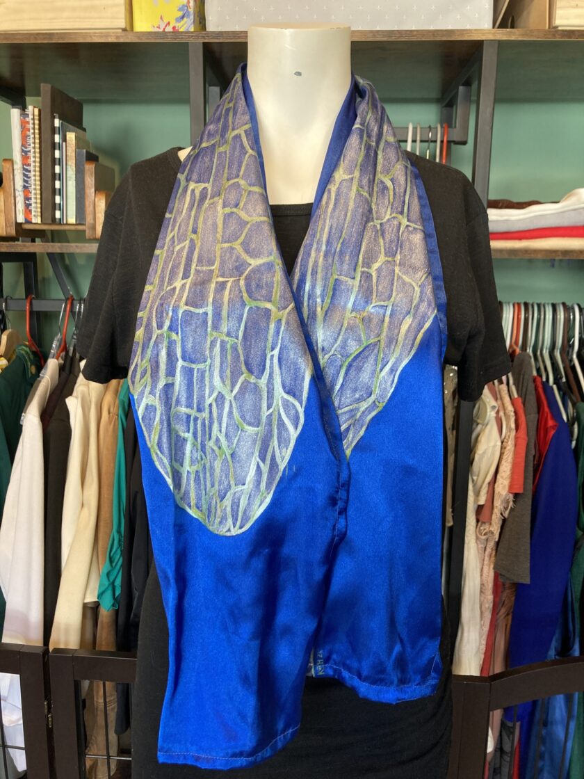 A mannequin wearing a hand-painted iridescent blue dragonfly wing scarf.