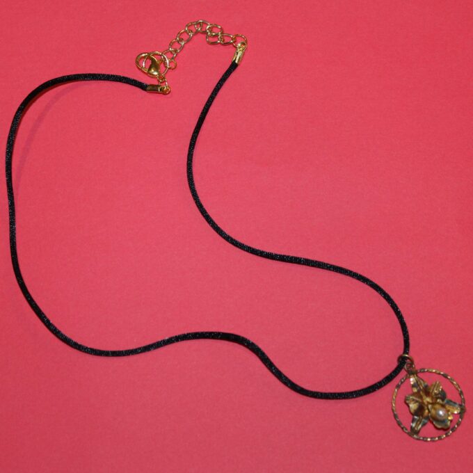 black silk cord necklace with antique weathered orchid pendant on red background