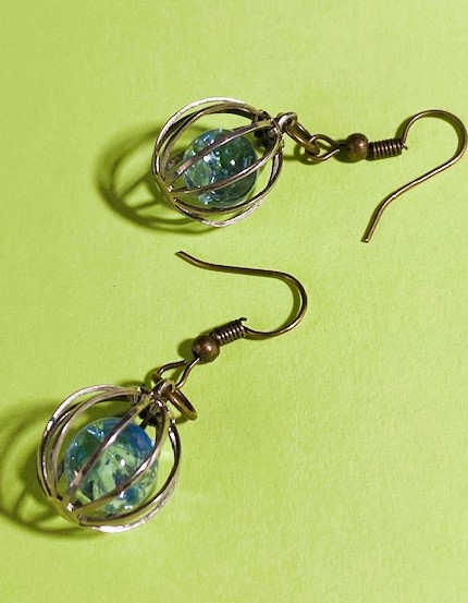 view of two pierced earrings with "caged" free floating blue bead in each