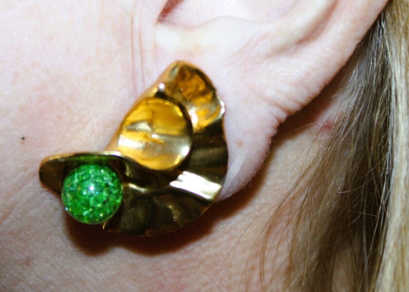 view of gold tone earring worn on one ear