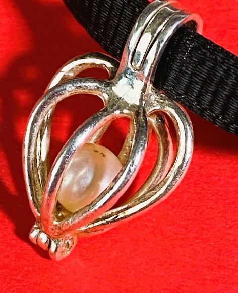 close up of silver heart cage with free rolling pearl encased