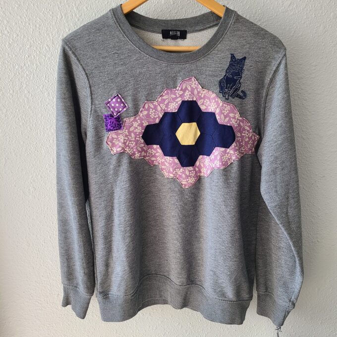 a gray sweater with a pink and blue design on it.