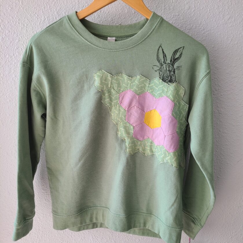 a green sweatshirt with a pink flower on it.