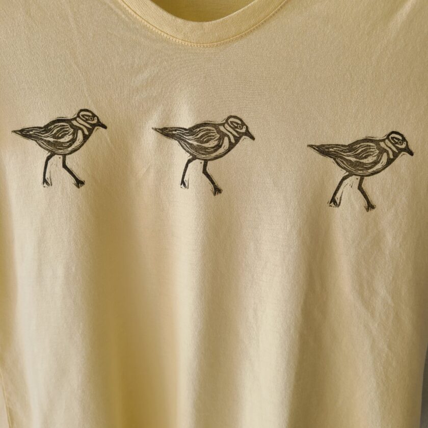 three birds on a yellow shirt with black ink.