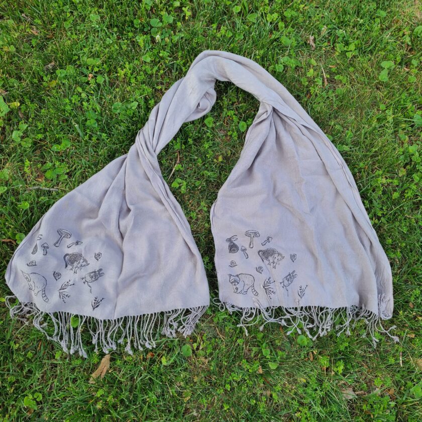 two scarves laying on the ground in the grass.