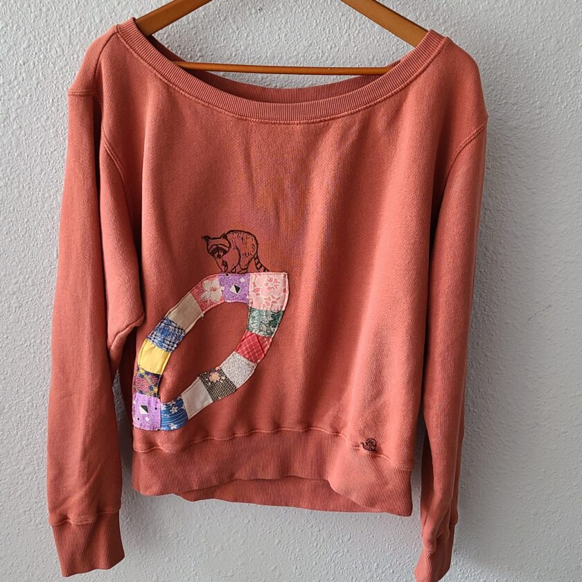 a sweater hanging on a hanger with a patchwork design on it.