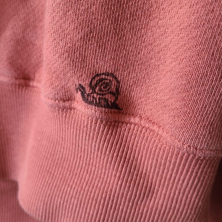 a close up of a pink sweatshirt with a logo on it.