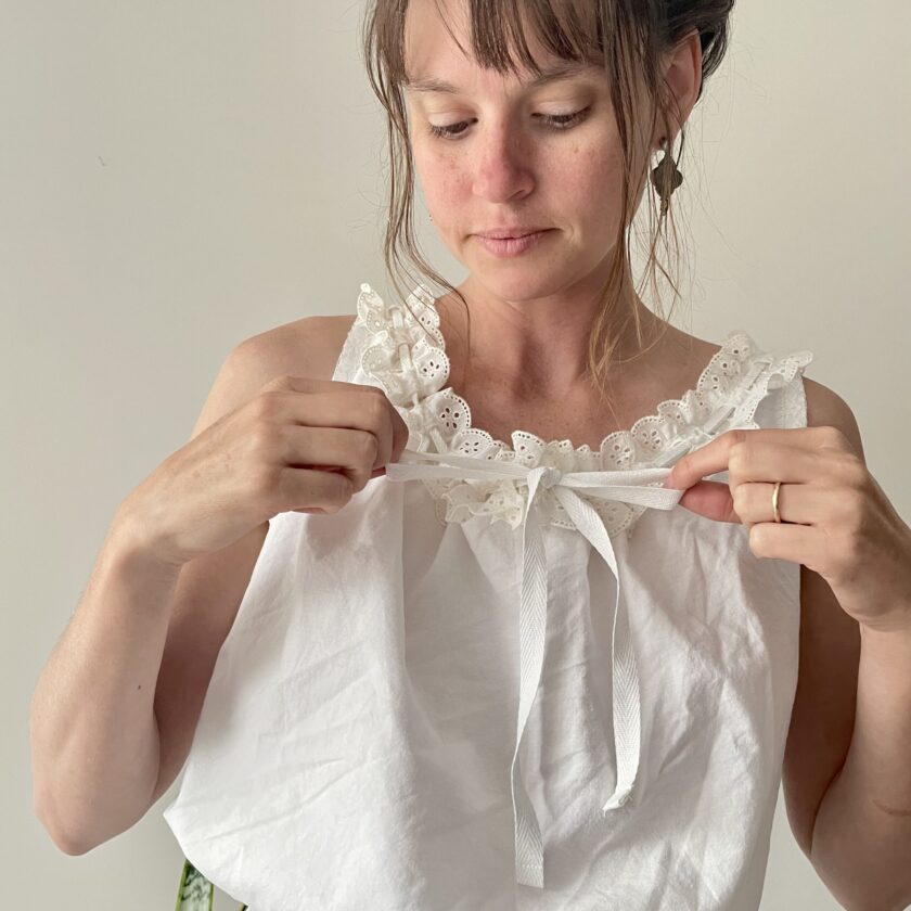 a woman in a white top is holding a piece of cloth.
