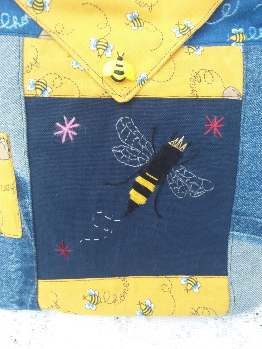 Hand embroidered queen bee upon a dark blue canvas background with honey bee fabric accents