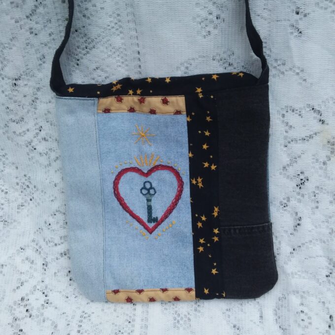 Eco-fashion designer handbag of denim and vintage textiles with artisan embroidered focal piece