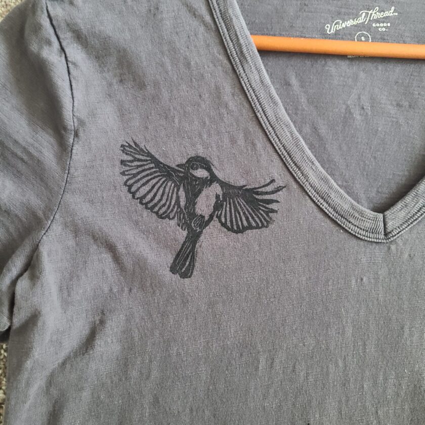 a gray t - shirt with a bird on it.