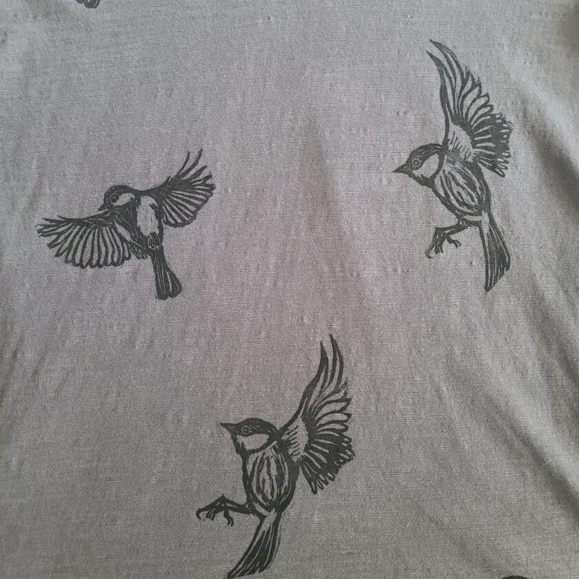 a grey shirt with black birds on it.