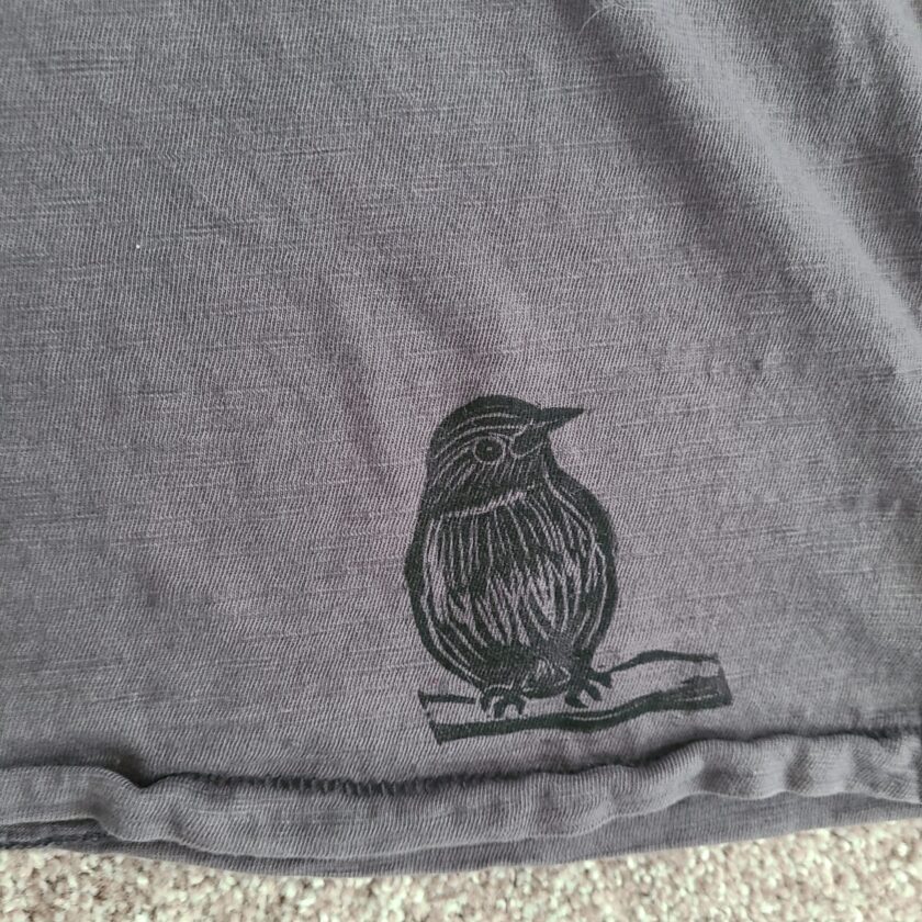 a grey t - shirt with a bird on it.