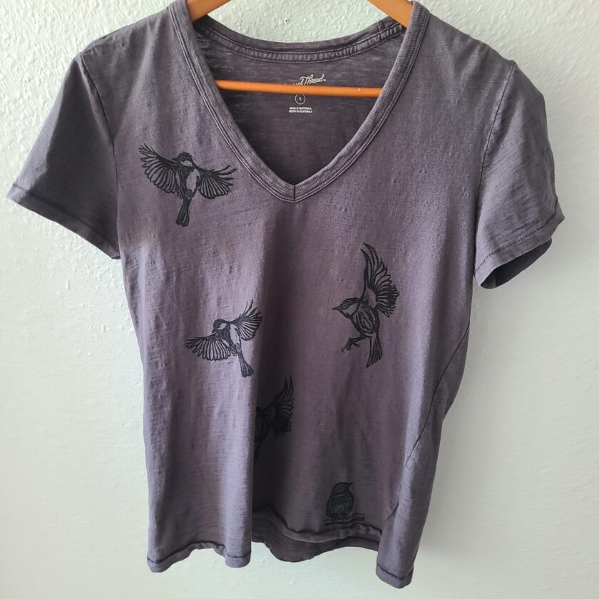 a gray t - shirt with black birds on it.