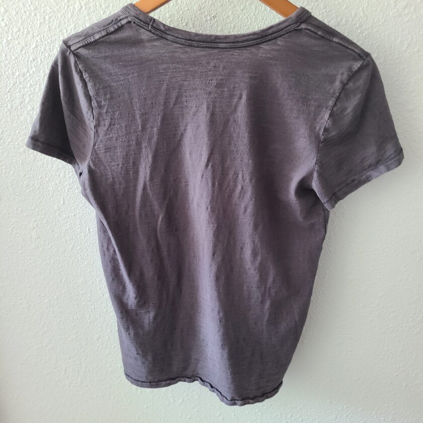 a grey t - shirt hanging on a hanger.