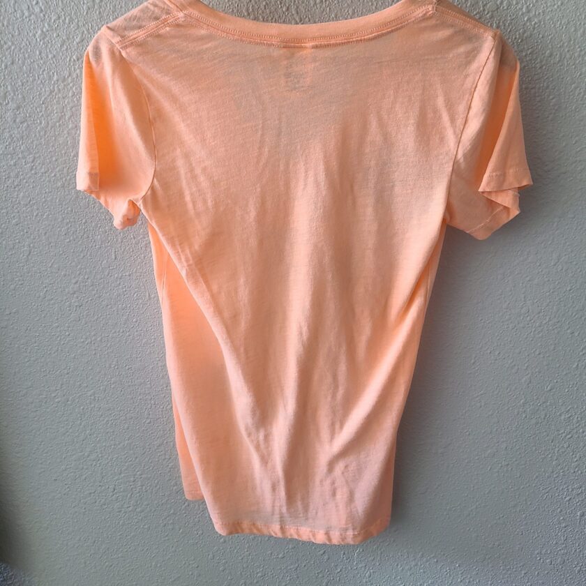 an orange t - shirt hanging on a wall.