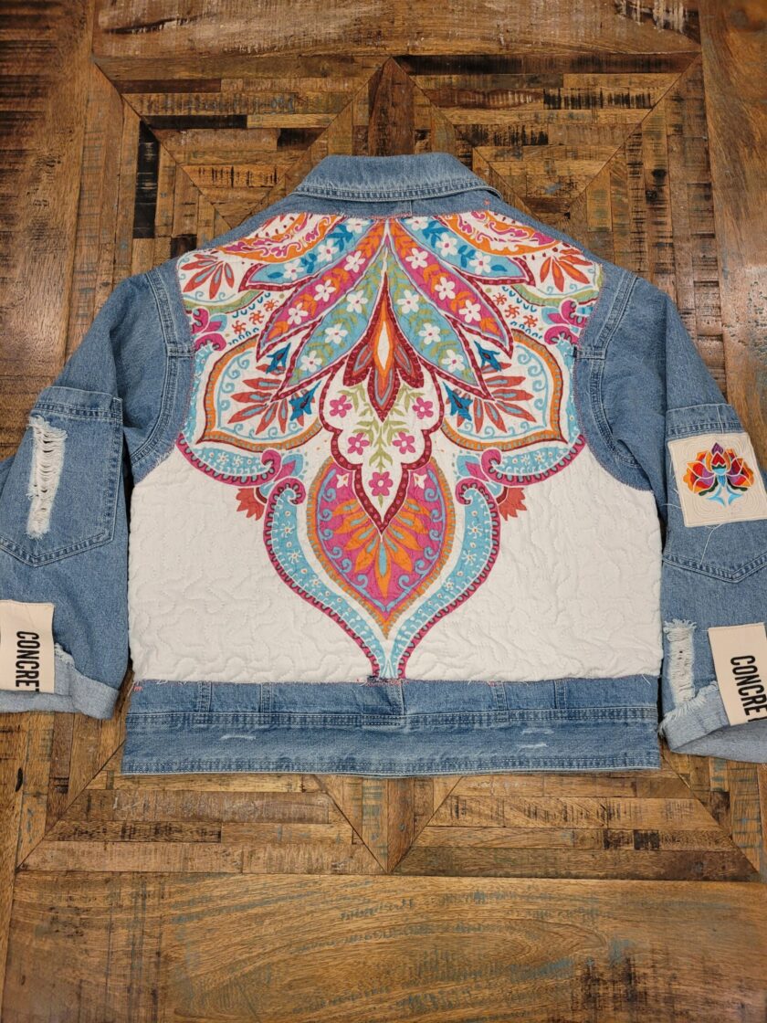 the back of a denim jacket with a colorful paisley pattern.