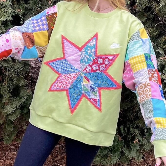 a woman wearing a green sweatshirt with a patchwork star on it.