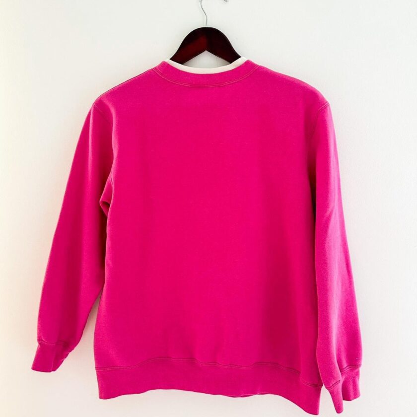 a pink sweatshirt hanging on a white wall.