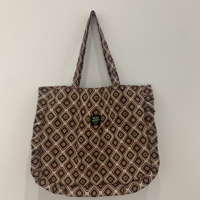 a brown and white tote bag hanging on a wall.