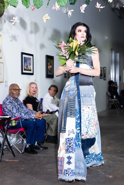 a woman is walking down the runway with a bouquet of flowers.