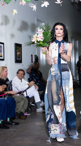 a woman is walking down the runway with flowers in her hands.
