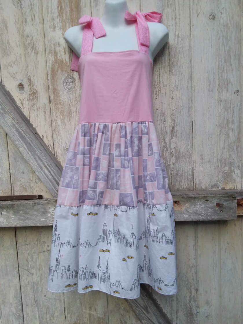 Upcycled layered sundress of pink and white fabric with geometric shapes and a city scape design