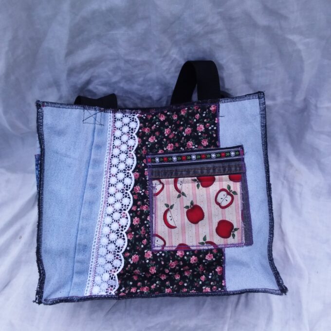 An upcycled denim tote bag with a patchwork pattern and pocket