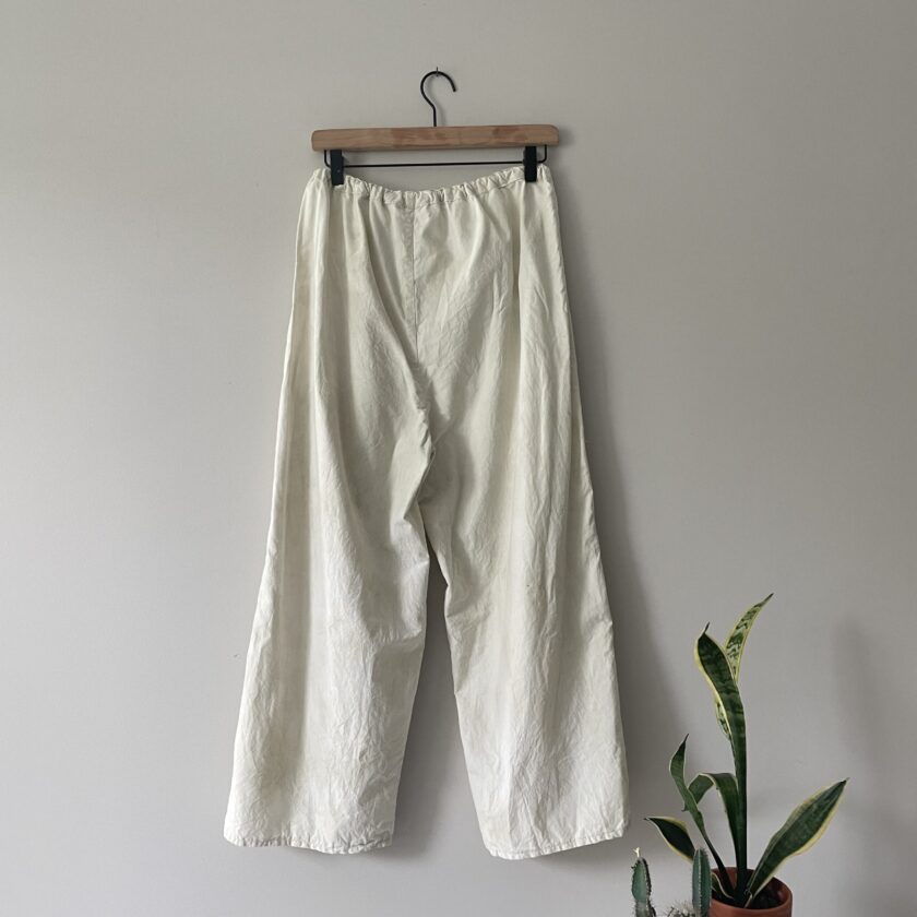 A pair of white wide leg pants hanging on a wall.
