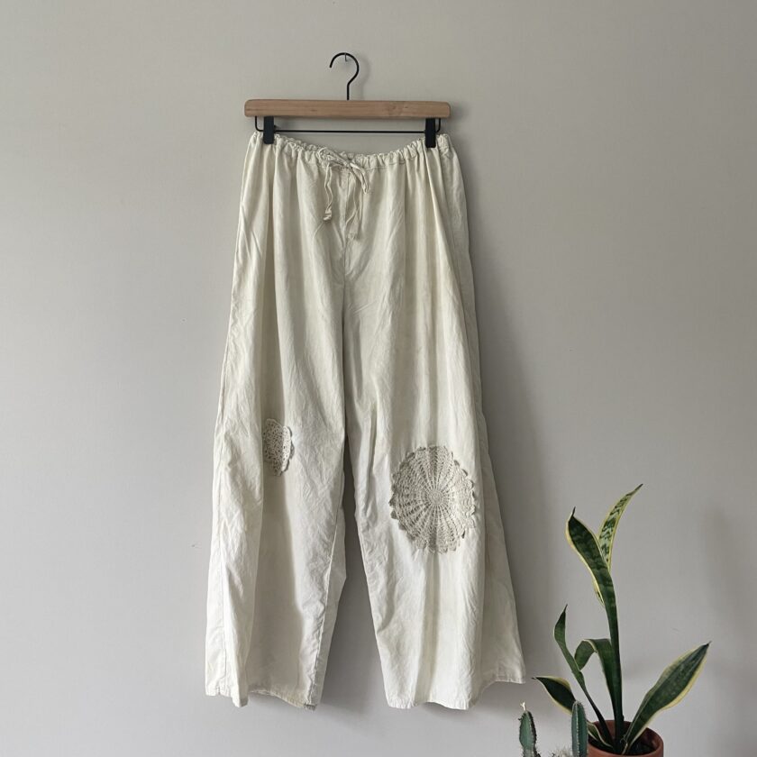 A pair of white pants hanging on a wall.