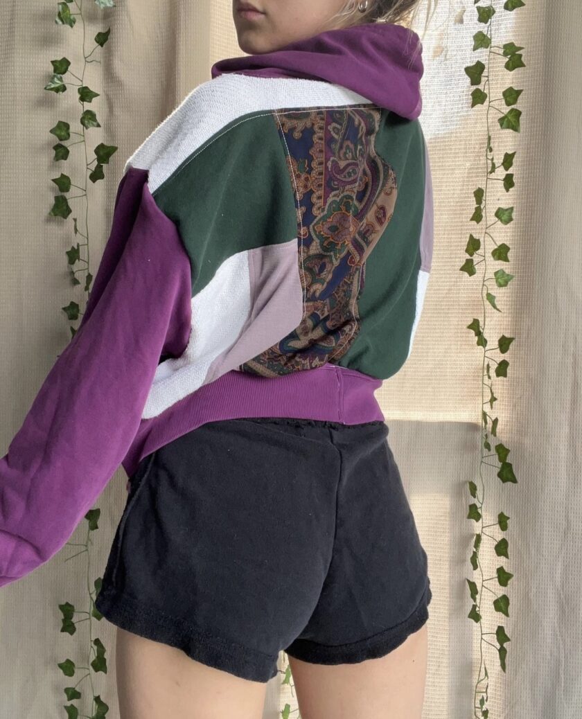 A woman wearing a purple hoodie and black shorts.
