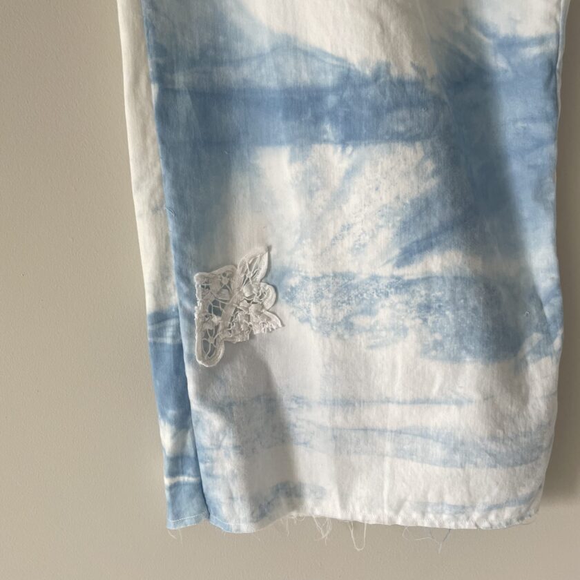 A blue and white tie dyed shirt hanging on a wall.
