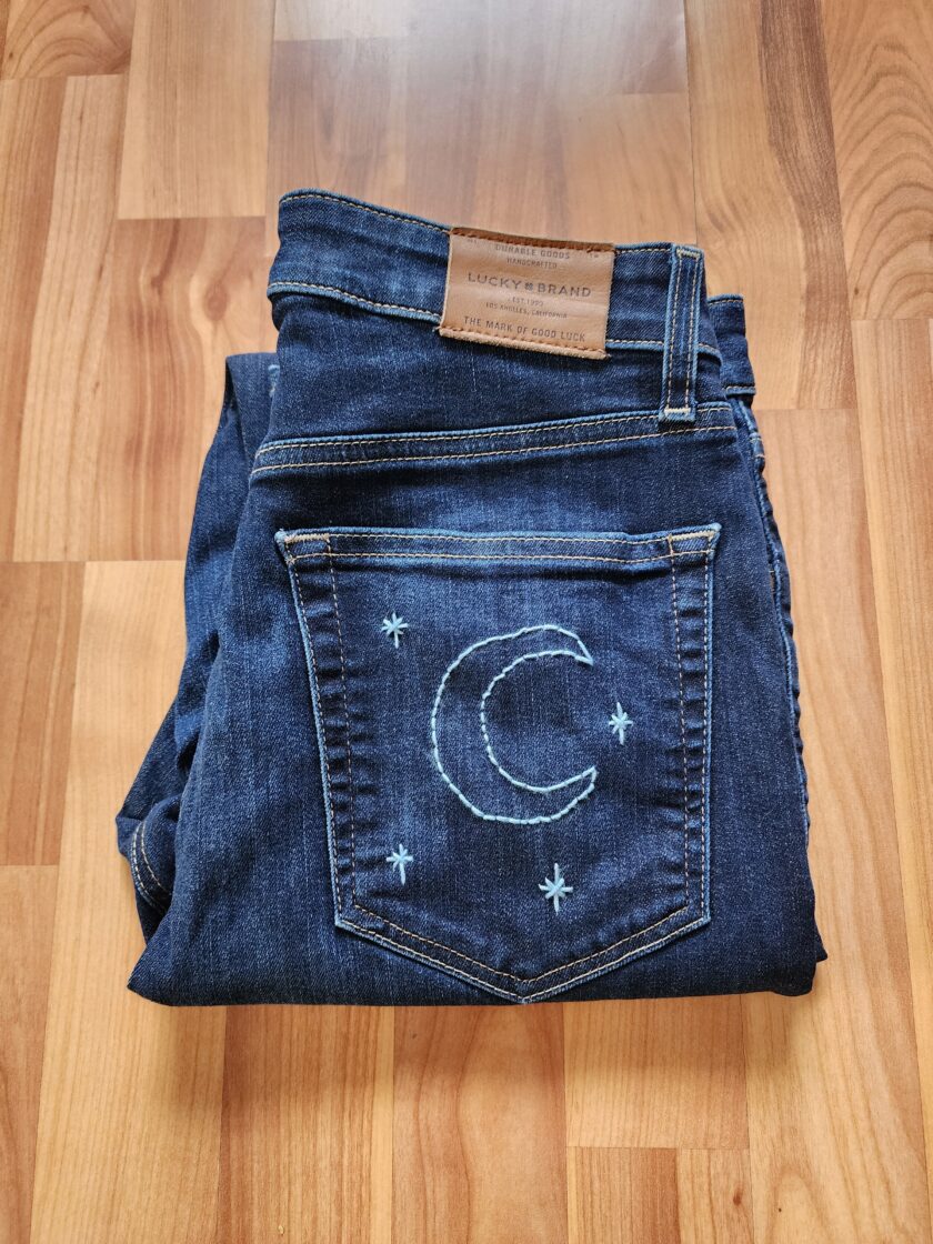 A pair of jeans with a moon and stars embroidered on them.