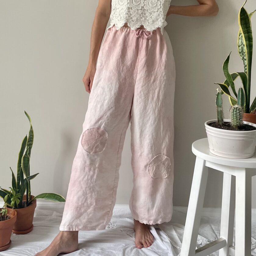 A woman wearing pink tie dye pants and a white top.