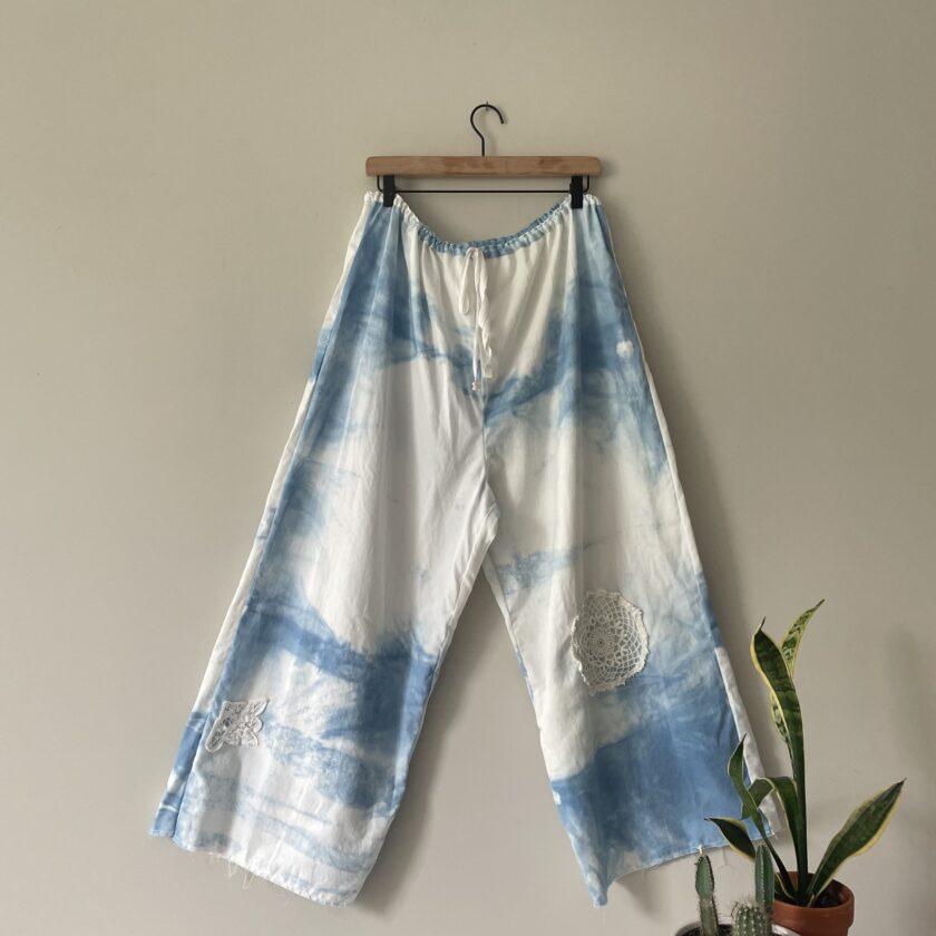 A pair of blue and white tie dye pants hanging on a wall.
