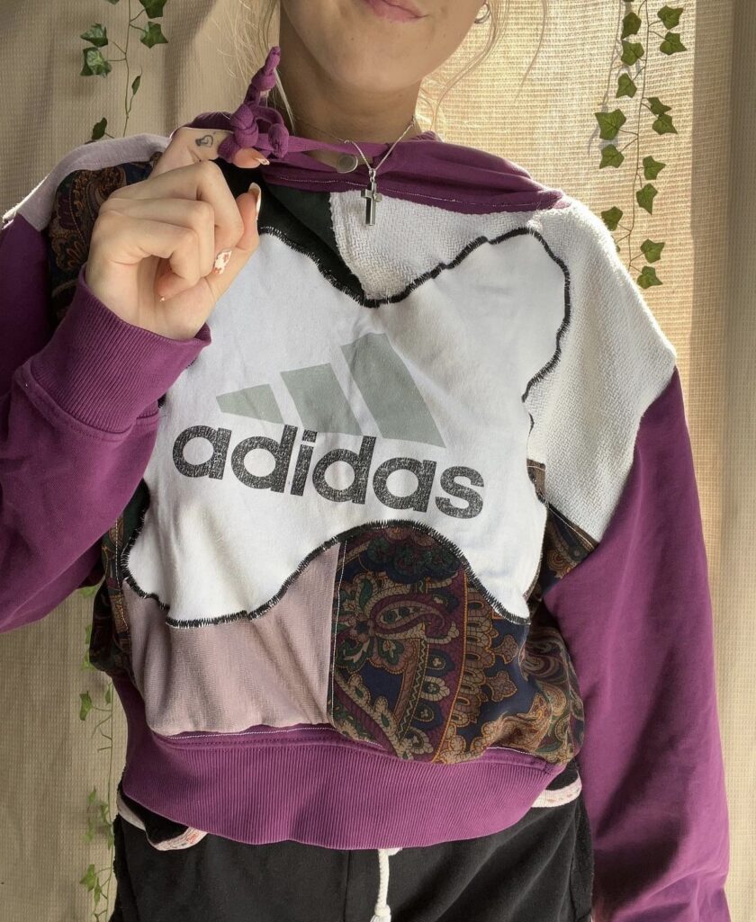 A woman wearing a purple and white adidas hoodie.