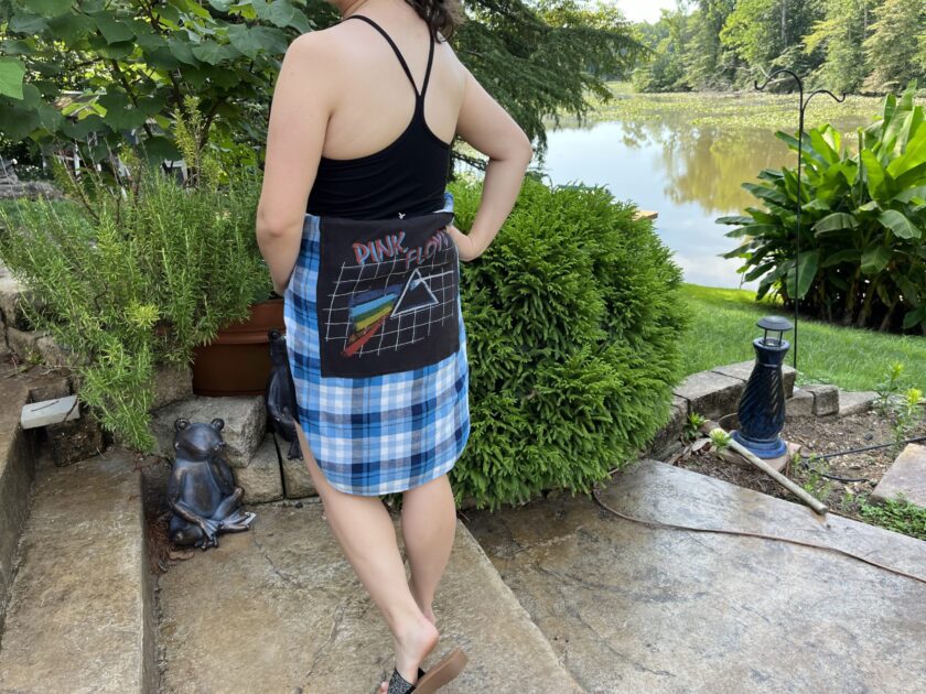 A woman wearing a plaid skirt standing next to a pond.
