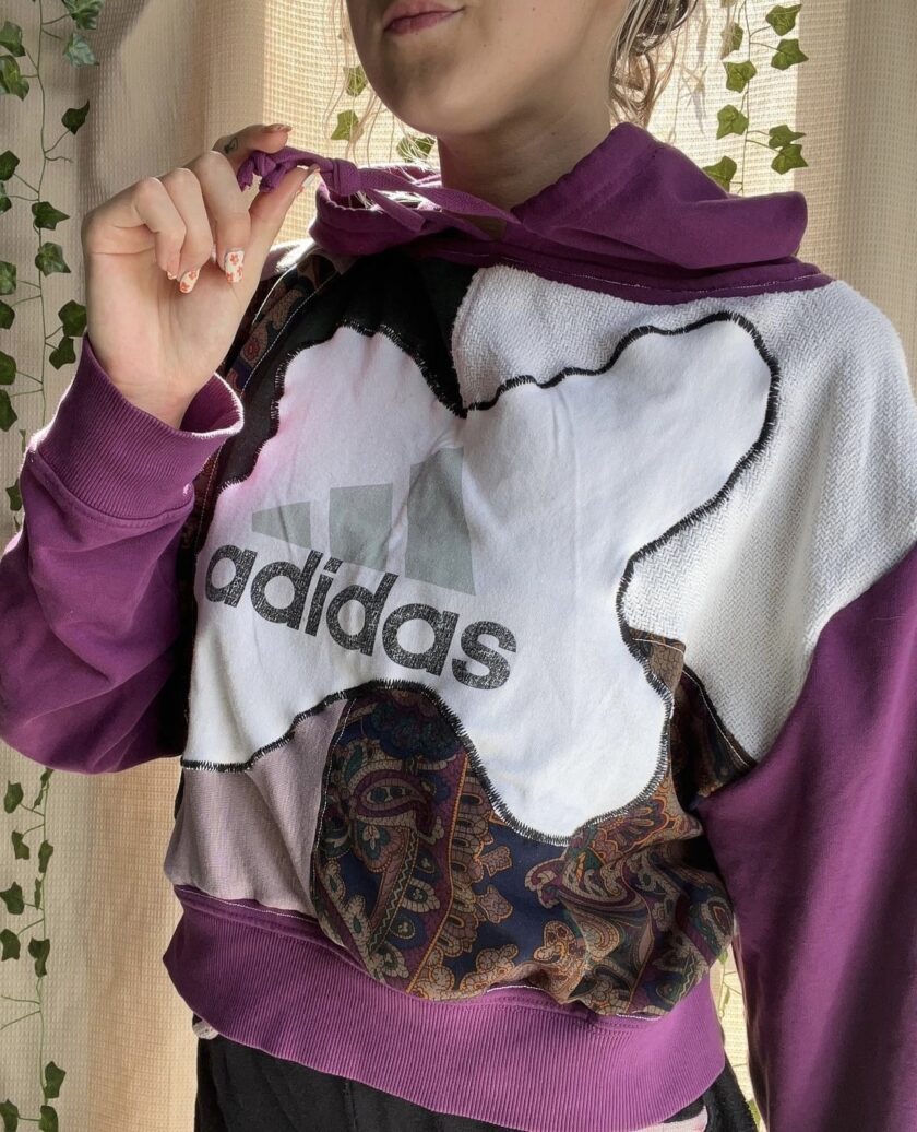A woman wearing a purple and white adidas hoodie.