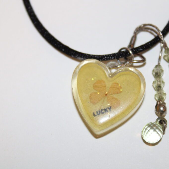 A heart shaped necklace with a yellow flower on it.
