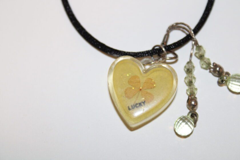 A heart shaped necklace with a yellow flower on it.