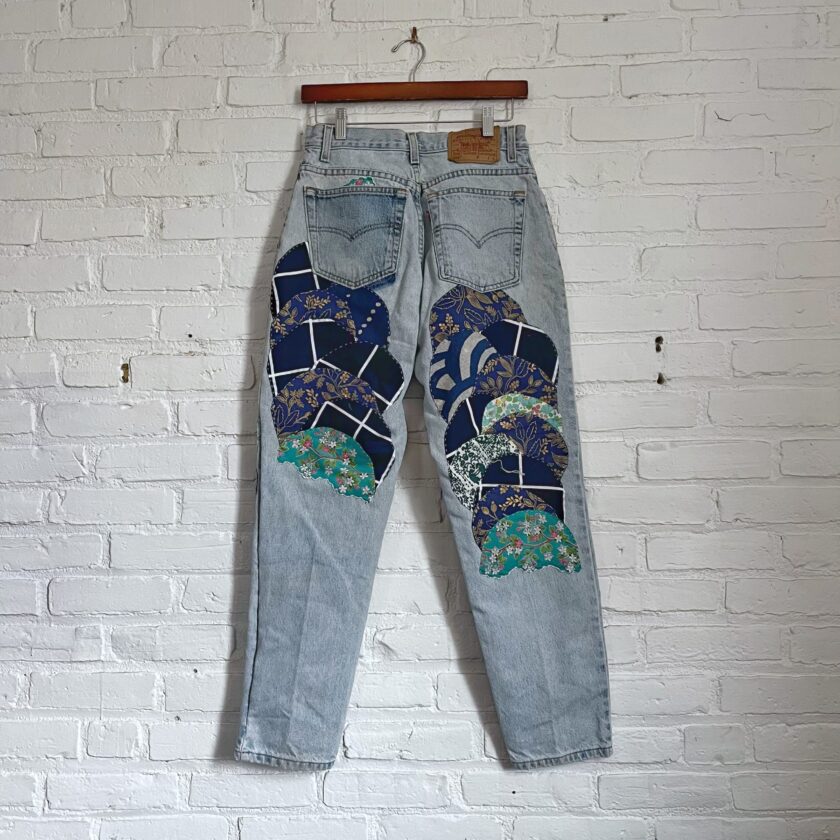 A pair of jeans with a blue and white pattern hanging on a brick wall.